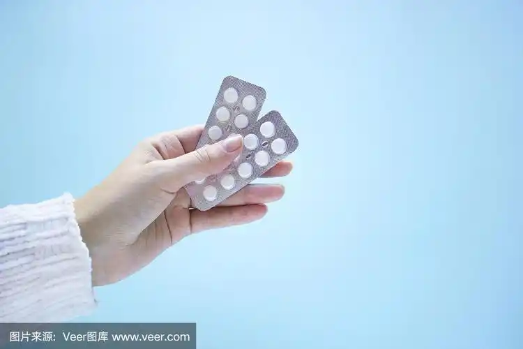 女人手里拿着两包蓝色背景的药片.
