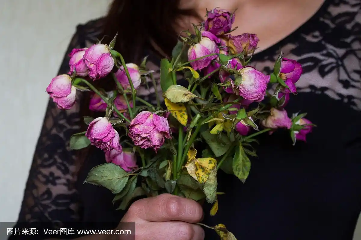 悲伤的女人拿着干枯的花束