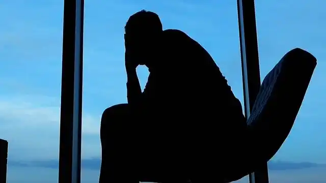 一男子独自坐在椅子上无奈悲伤思考生意失败