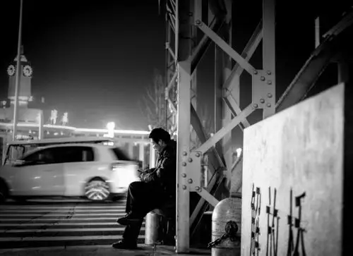 解放桥上车来车往,川流不息,一个男人坐在桥头安静的看着手机,也许这