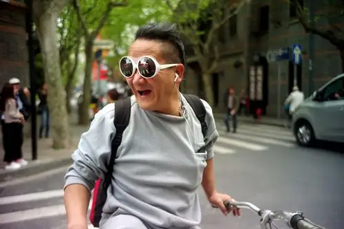 这位老爷叔老时髦的戴着白框大墨镜,骑着城市休闲车,热呵呵地同人聊着