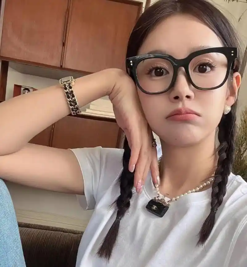 张子萱坐在沙发上自拍,戴着黑框眼镜像是学生,都快40还和20年前一样