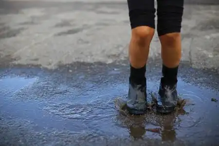 穿雨靴的孩子跳进水坑里照片