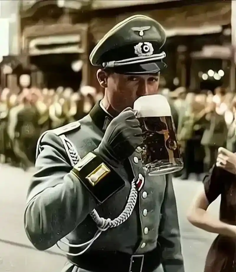 二战时一名德国军官在柏林街头大口喝着一扎啤酒.