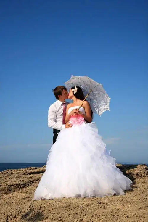 新郎和新娘接吻,年轻的新娘和新郎接吻在海滩上的肖像