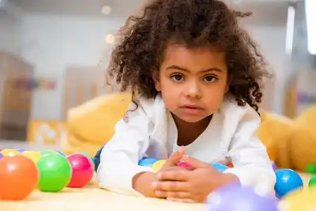 美国社区幼儿园可爱的非洲裔美国孩子躺在地毯上的玩具在幼儿园和看