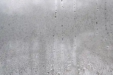 质地的一滴雨在玻璃湿透明的背景上.灰色色调照片