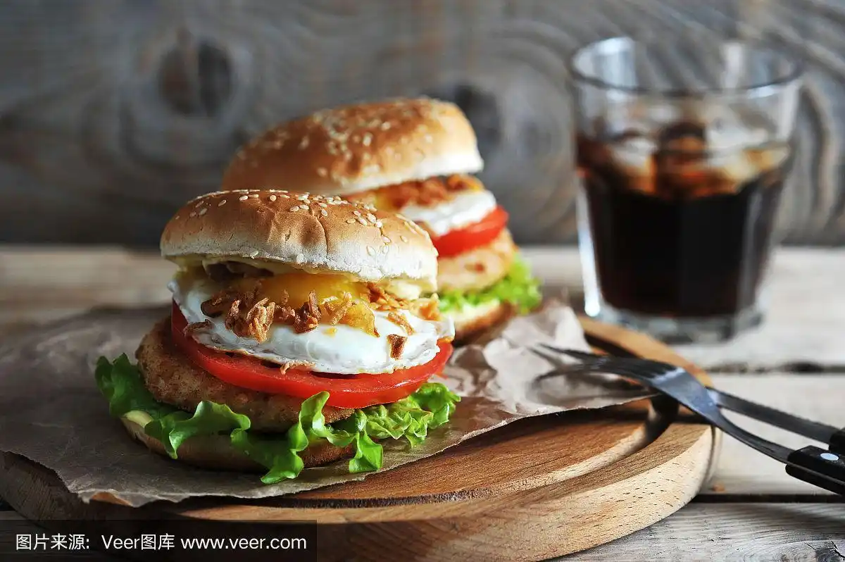 鸡肉汉堡配鸡排,番茄片,煎蛋,青菜沙拉和酱汁.