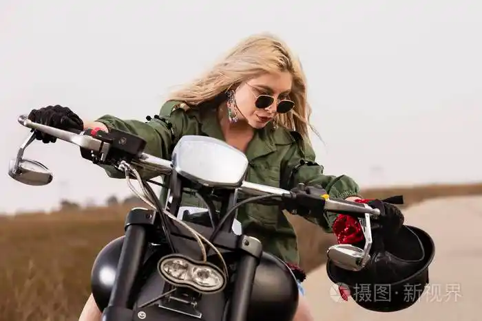 一个年轻漂亮的女人坐在一辆黑色和镀铬的摩托车上