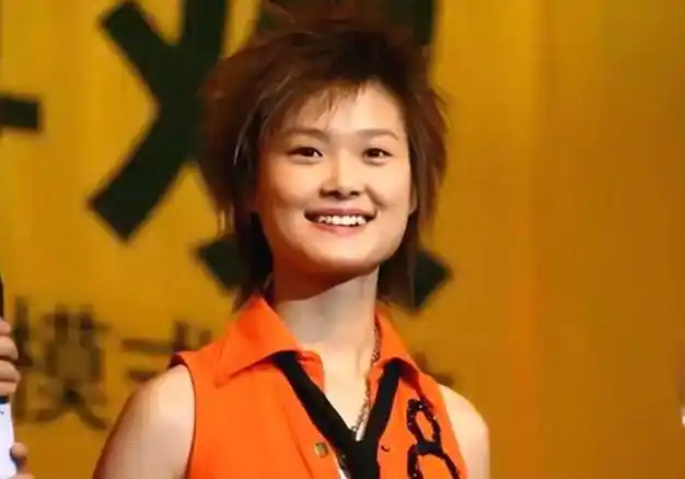 照片中的李宇春,身穿宽大的蓝色衬衫和短裤,一头短发随风飘动,笑容
