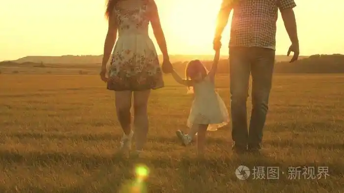 孩子和爸爸妈妈在夕阳下玩耍.和一个小孩子在大自然中散步.