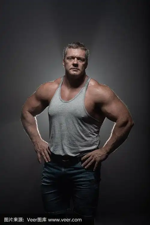 一个强壮的肌肉健美者在一个黑色的背景摆姿势.力量和健康的概念