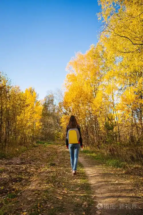 一个背着背包的年轻女子独自在秋天散步