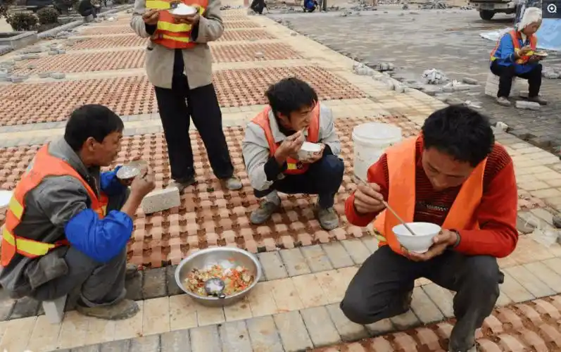 贵州省凯里市,建筑工地上的环卫工人蹲在地上吃午餐,菜盆里面只有蔬菜