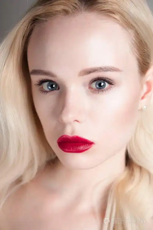 完美的化妆美容模型女孩红红的嘴唇和蓝色的眼睛看着照相机.