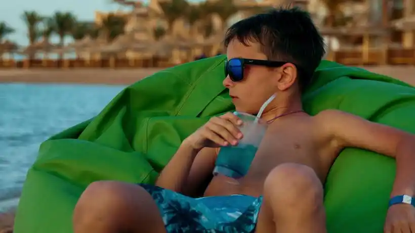 小男孩暑假在海边喝柠檬水玩得开心