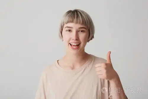 室内拍摄的微笑年轻女孩保持大拇指, 显示她的同意或协议, 隔离在白色