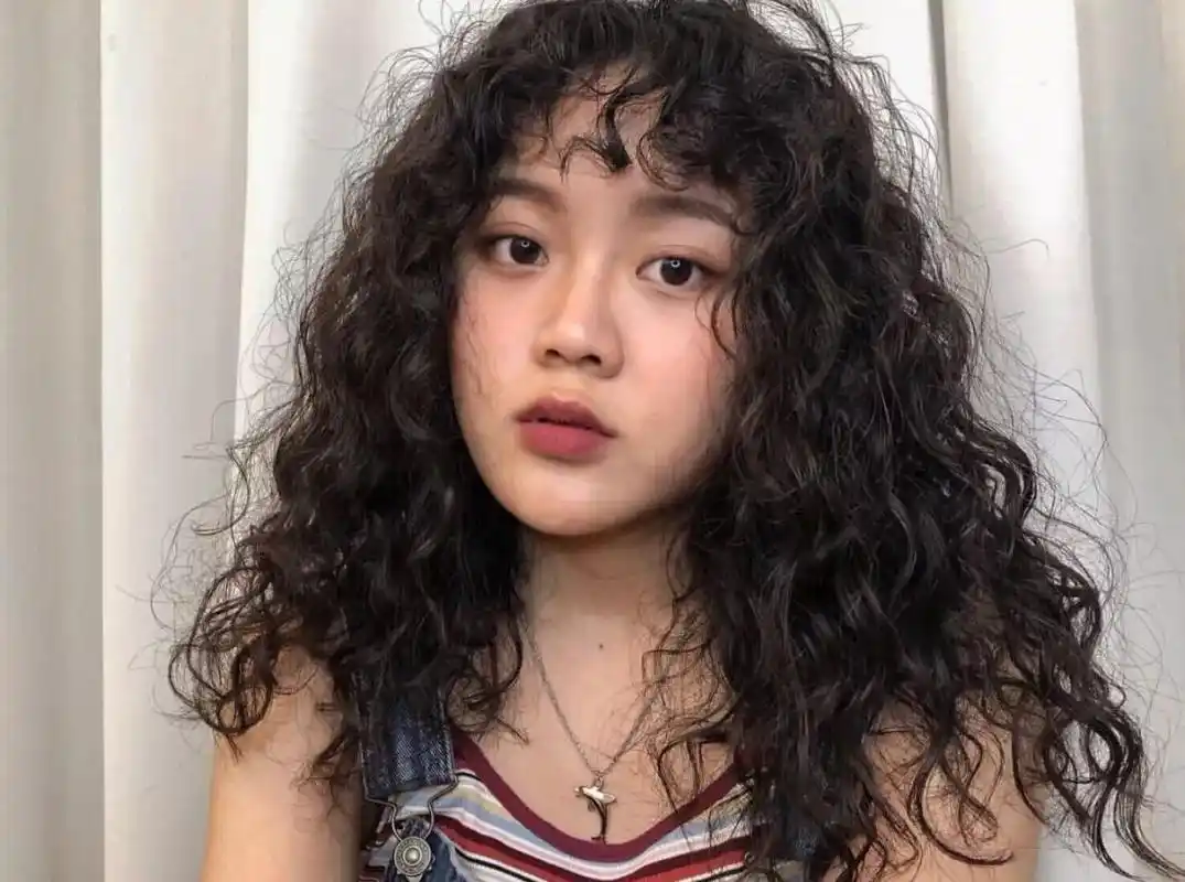 女生一头羊毛卷发型加上短短的狗啃刘海,显得很是