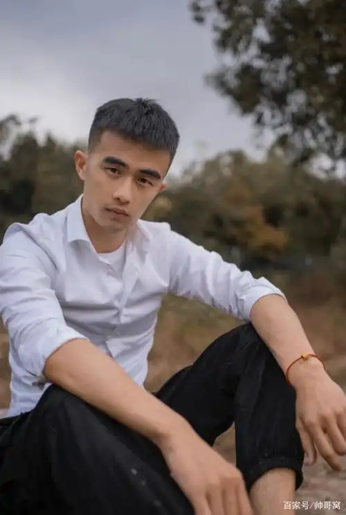 清瘦的男生,穿着白颜色衬衫坐在草地上,远看真是一道不错的风景