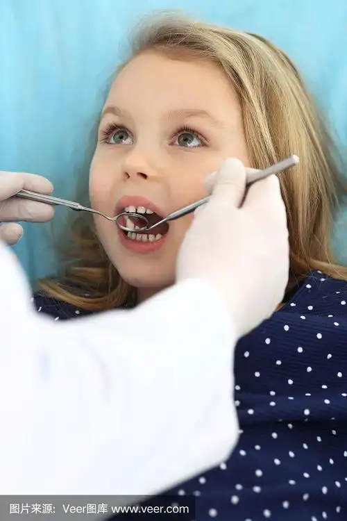 小女孩张大嘴巴坐在牙科椅上接受医生的口腔检查.拜访牙医的办公室.