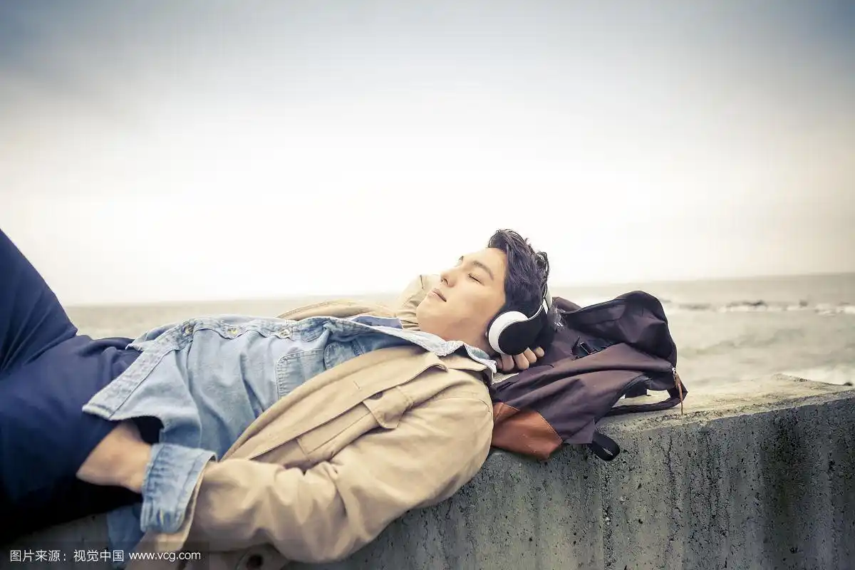 一个人躺在海边用耳机听音乐的照片