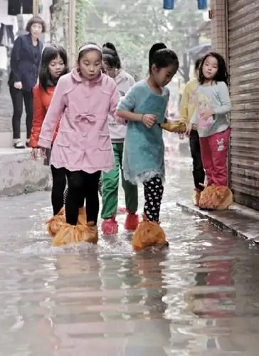 小学生穿着自制"水鞋"蹚水.