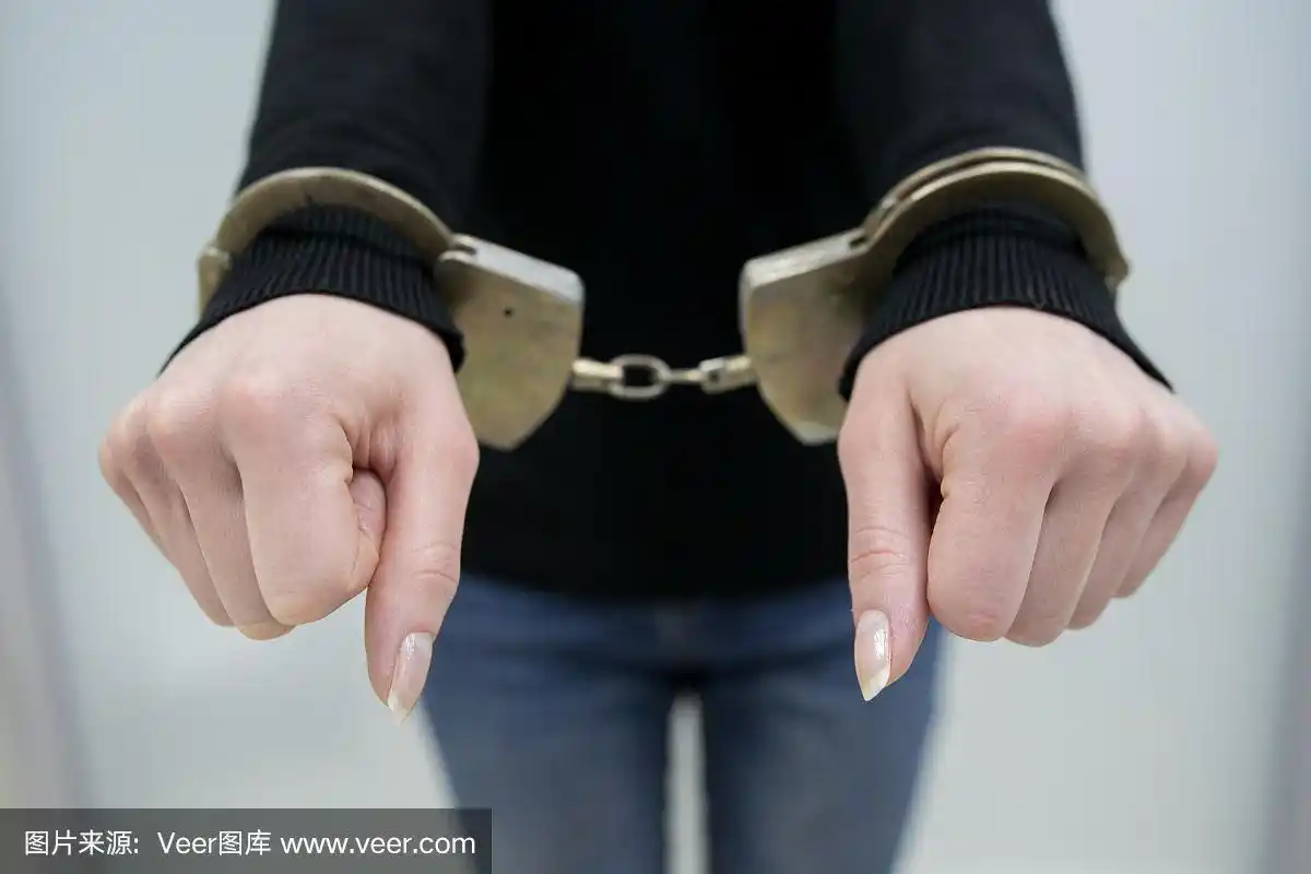 被逮捕的男子双手戴着手铐,在灰色背景下孤立.