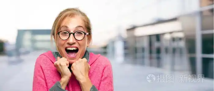 美丽的成年金发女郎带着高兴的表情, 睁大了双眼, 张开了笑容, 双手