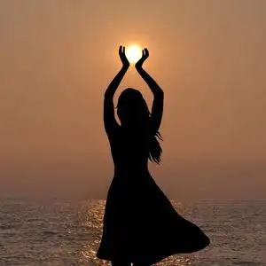 年轻女子手捧太阳的剪影照片