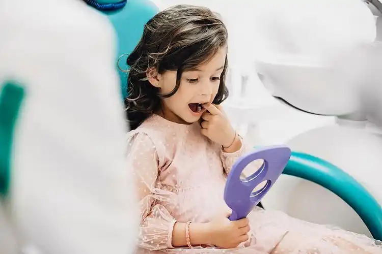 可爱的小女孩看她的牙齿手术后在儿科口腔医学.照片下载