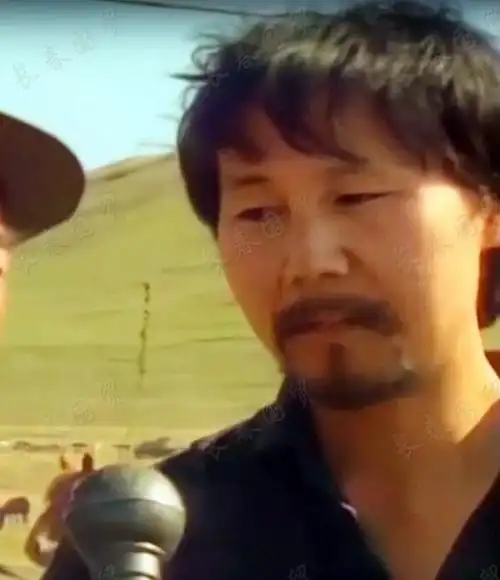 照片中,当时年仅28岁的腾格尔身穿衬衫,站在大草原上正在接受采访.