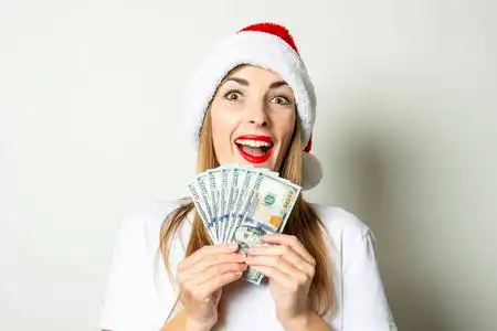 一位戴着圣诞老人帽子的年轻女子,在白色背景下,手里拿着一沓钱.