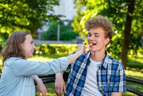 一个女孩正在喂一个人吃东西.那家伙笑得很开心.幸福关系的概念