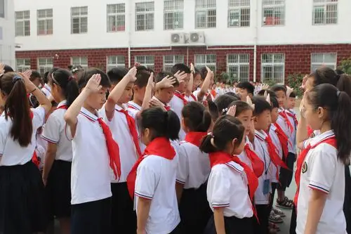 大队辅导员杜老师带领新少先队员在队旗下宣誓,表达自己的决心.