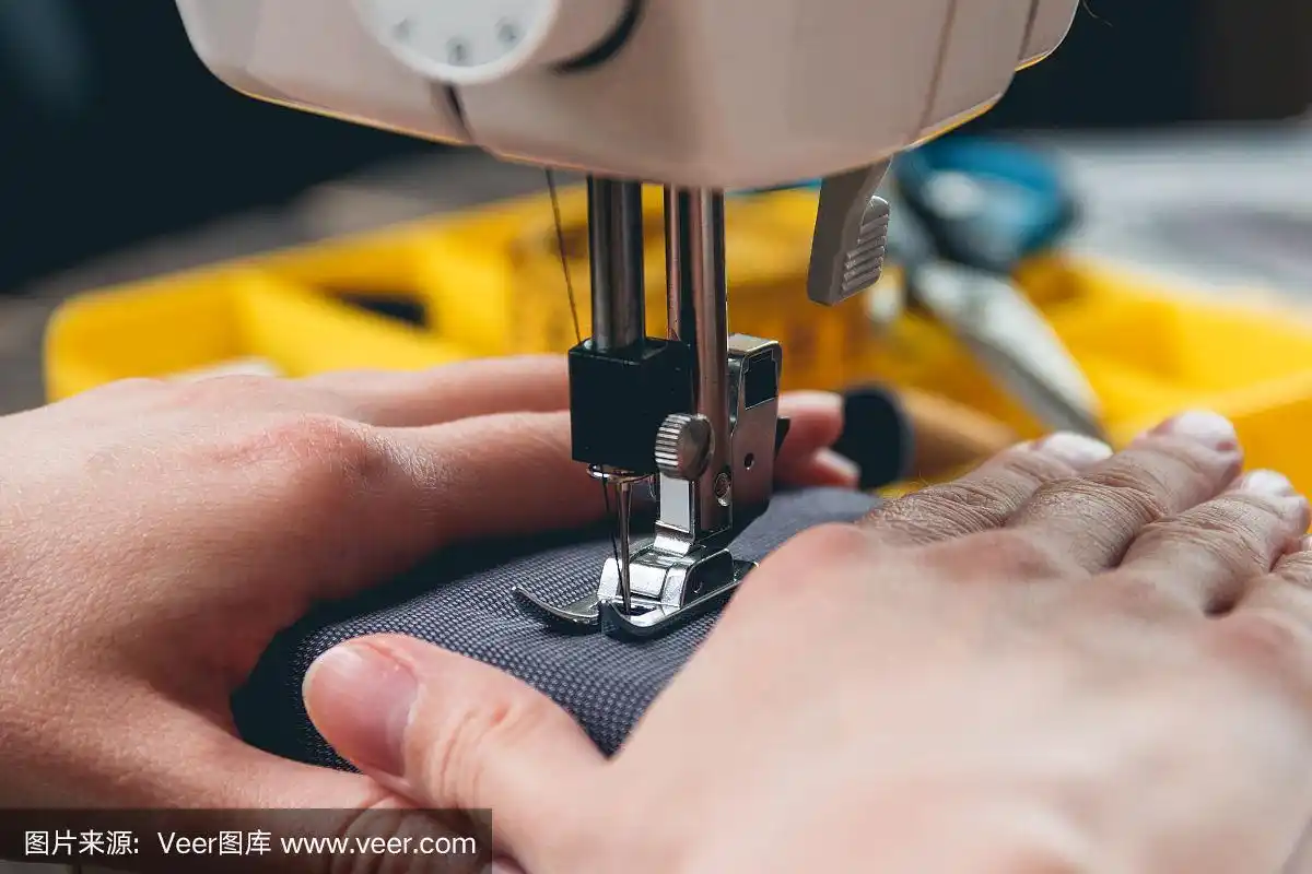 年轻女孩的手在缝纫机上