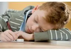 教室里趴着课桌上写字的小男孩图片素材