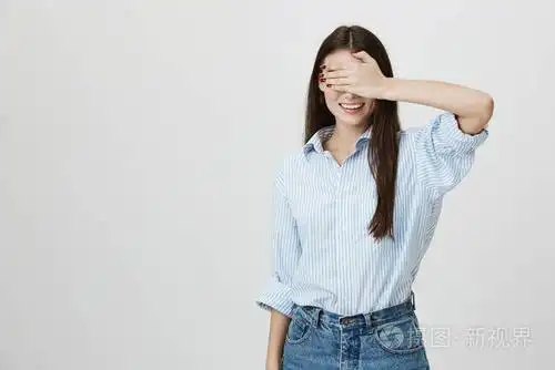 工作室肖像年轻漂亮的年轻女士用手捂着眼睛, 兴奋地笑着, 等待着灰色