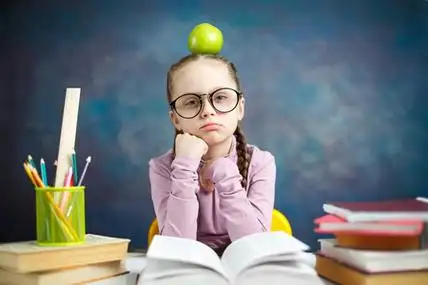 聪明的小学生读教科书,有吸引力的孩子长辫子戴眼镜.