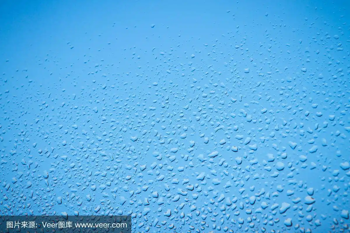 雨滴落在窗户上作为纯蓝色的背景