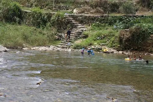 路边小河很浅,河水清澈,很多壮族小朋友在河里游泳.
