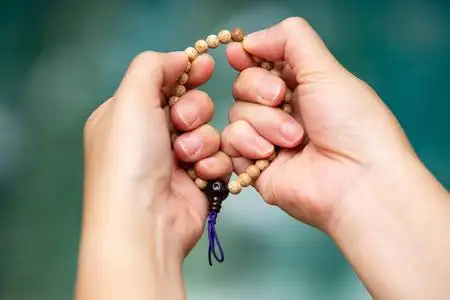 妇女双手祈祷,手持念珠在博凯蓝色游泳池背景,亚洲肢体语言感觉,祈祷