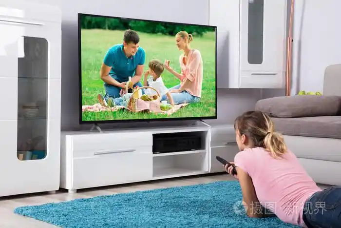 躺在蓝色地毯上,手里拿着遥控器,在家里看电视