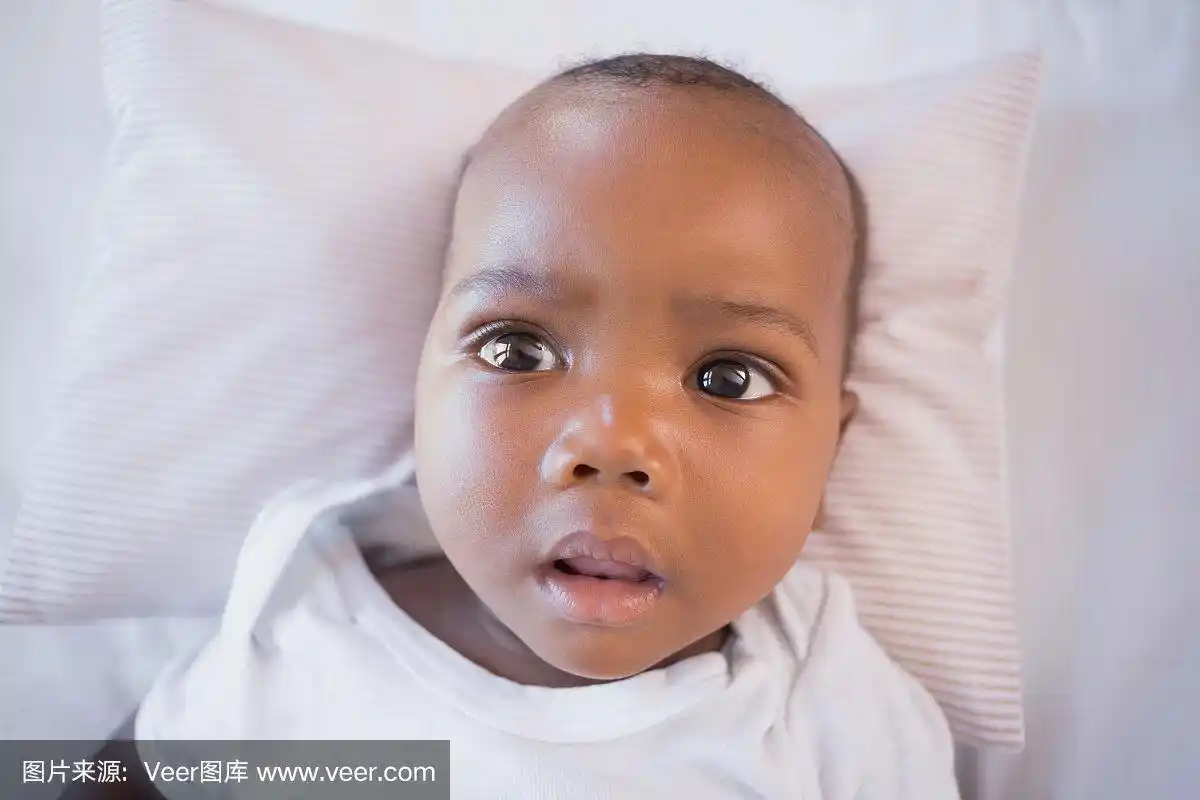 可爱的小男孩躺在他的婴儿床里