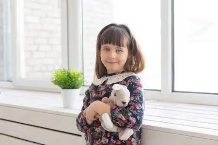 一个可爱善良的小女孩穿着花裙,手里拿着一只心爱的小兔子在玩玩具,站