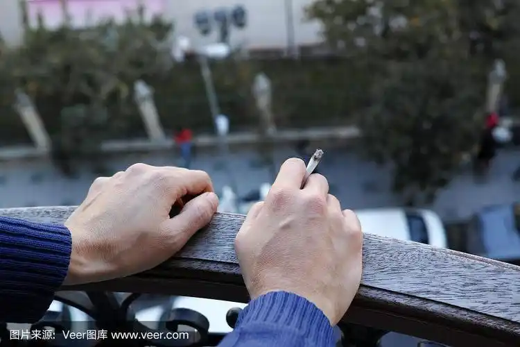 窗边的男人,手指间夹着香烟