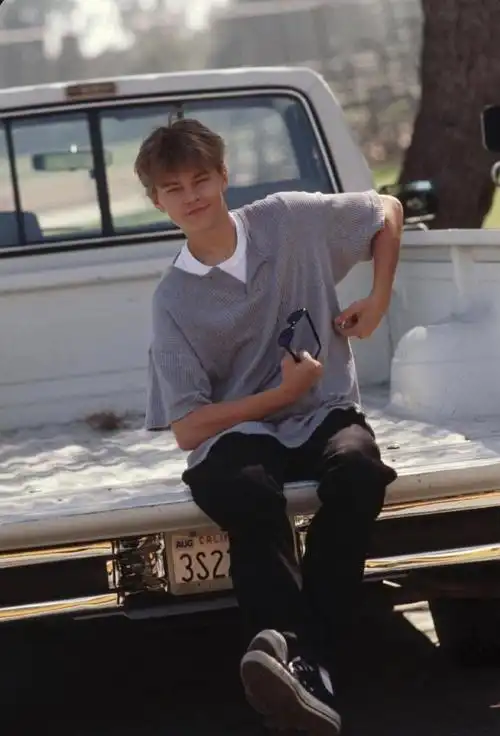 十几岁的小李子身穿灰色针织t恤,搭配白色的t恤,休闲裤和休闲鞋,阳光