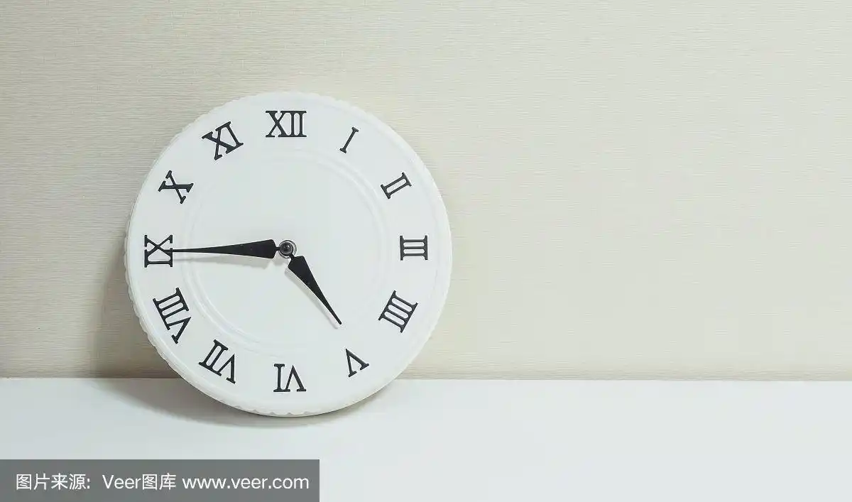 近距离白色时钟装饰显示下午四刻钟或下午四点四十五在白色木质桌子和