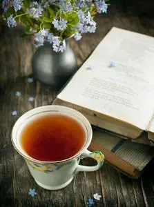 桌上有一杯茶,古书和蓝色的花.照片
