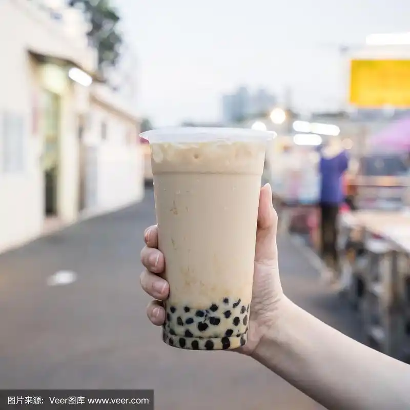 一名年轻女子正拿着塑料杯的红糖奶茶在台湾夜市,台湾美食,关门.