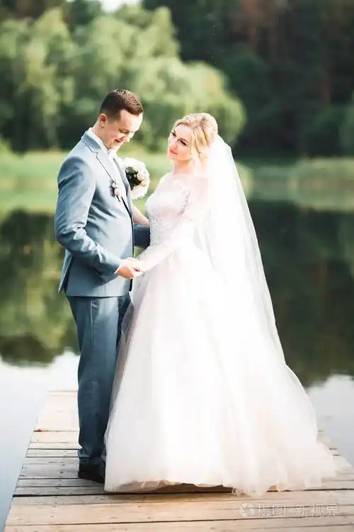 浪漫的婚礼时刻,一对新人微笑着画像,新郎新娘拥抱在一起照片-正版